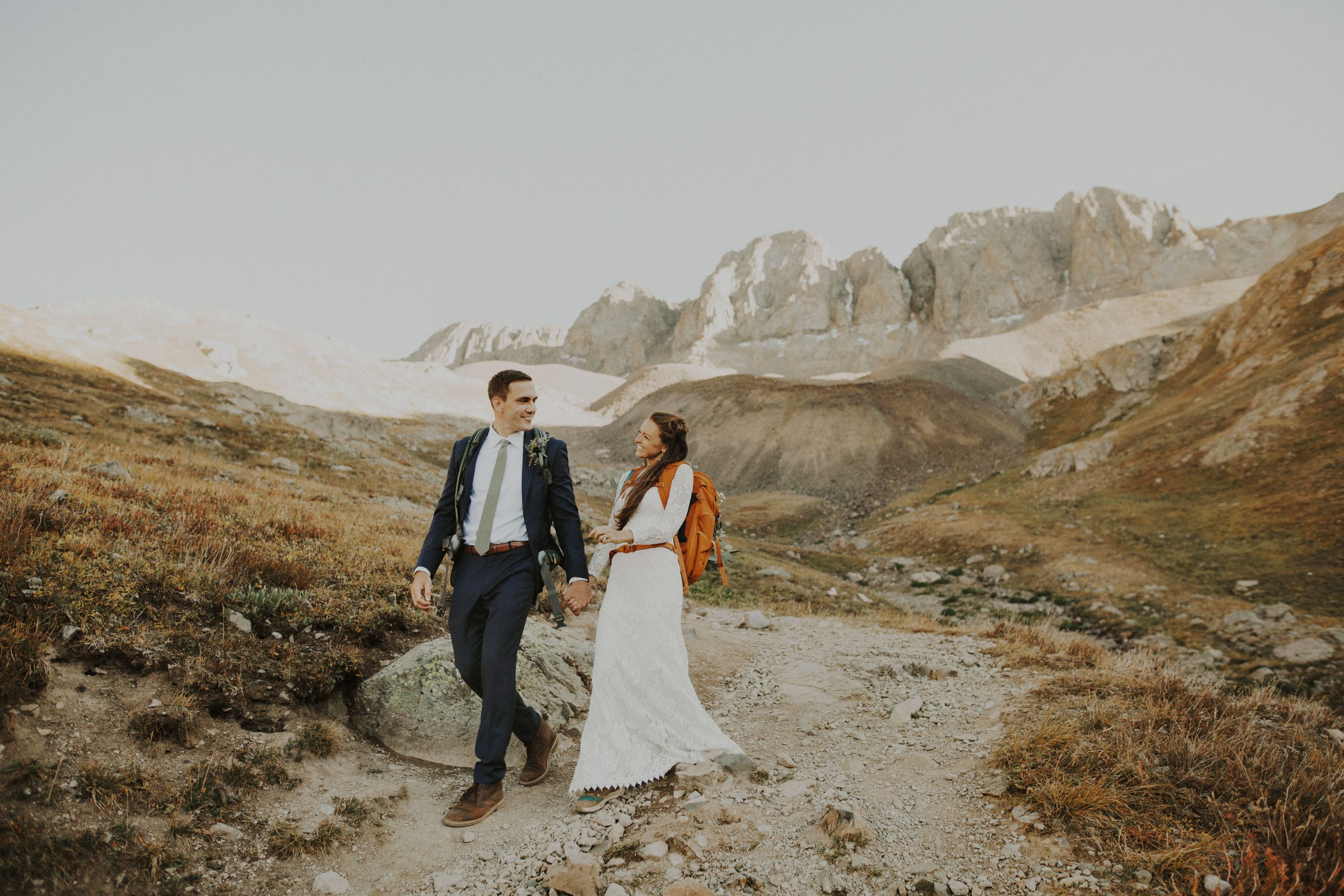 Bride and groom holding hands as they walk down the American Basin hiking trail.