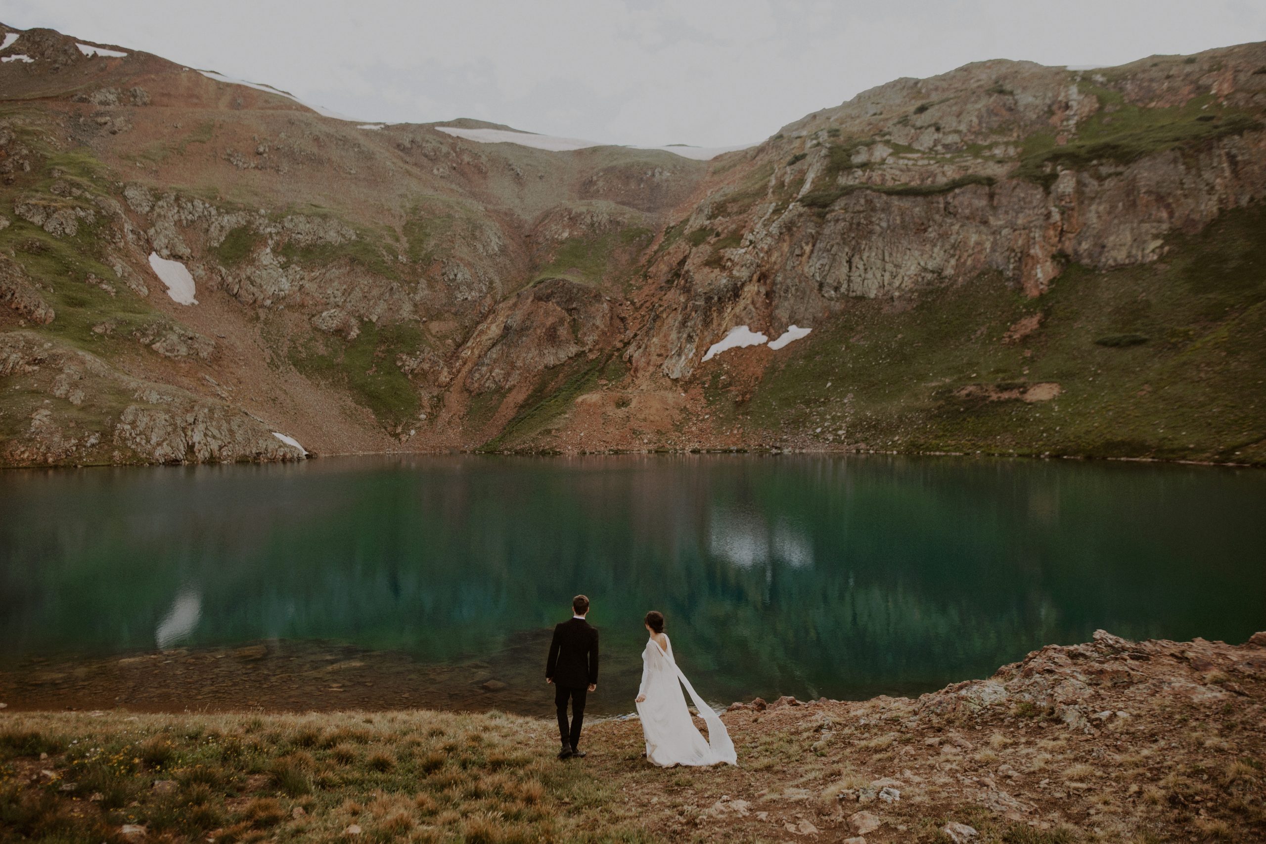 Couple stands in front of alpine lake in Telluride